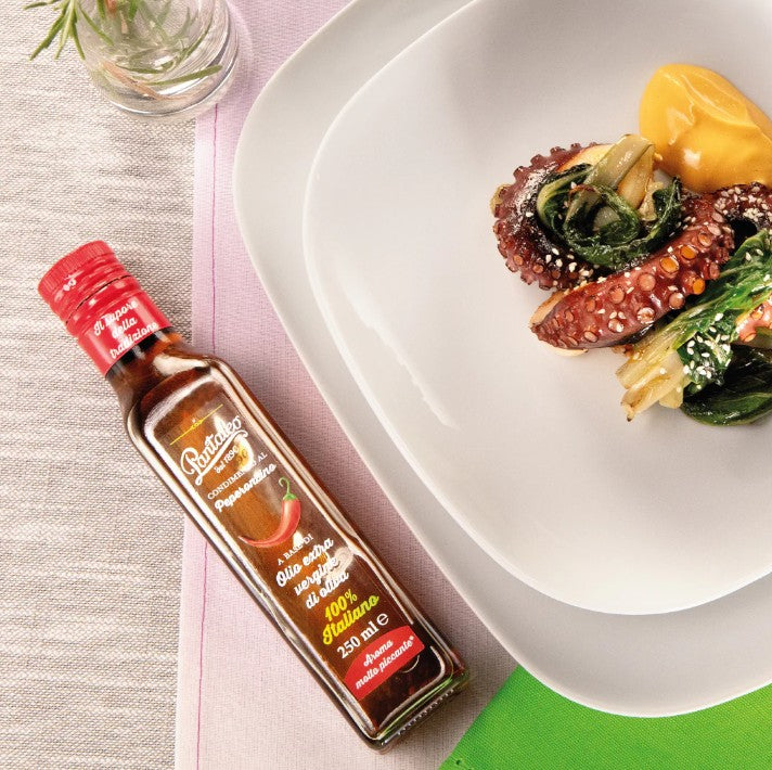Bottle of Pantaleo chilli Extra virgin olive oil next to a plate of food on a table